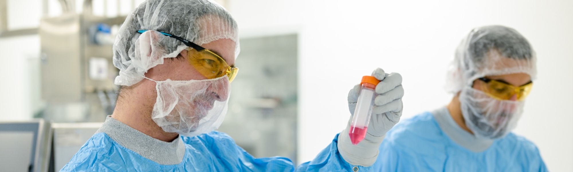 Man looking at a vial of fluid in the lab